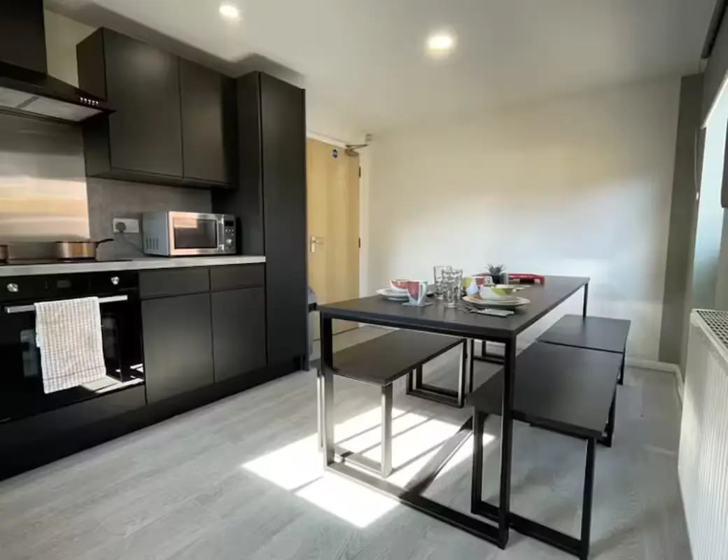 Black cabinets microwave oven dining table kitchen at Queens Court Leicester in Leicester Student Accommodation