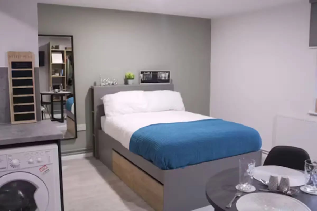 Bed with blue throw study area kitchen area bedroom at Queens Court Leicester in Leicester Student Accommodation