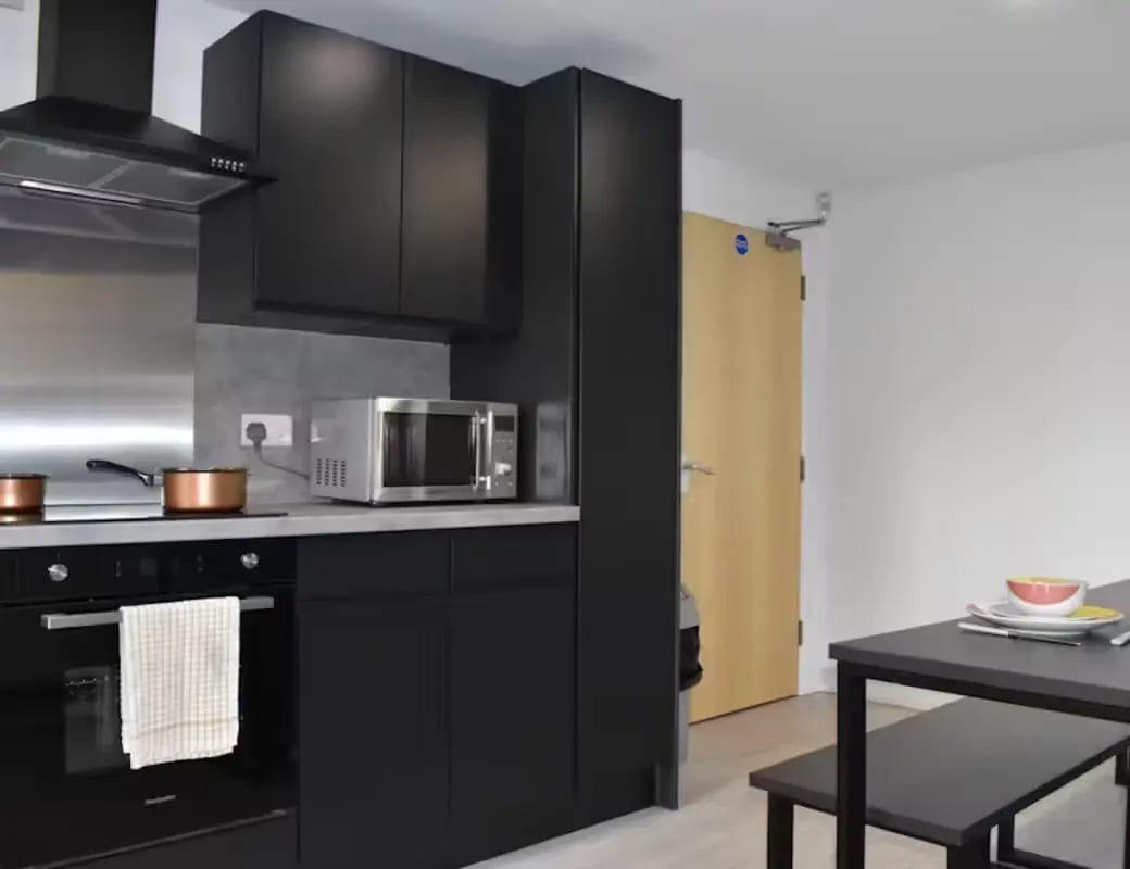 Modern black cabinets microwave oven stove kitchen area at Queens Court Leicester in Leicester Student Accommodation