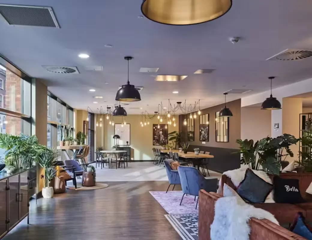 Lounge with sofas tables plants and chairs common area at York House in Nottingham Student Accommodation
