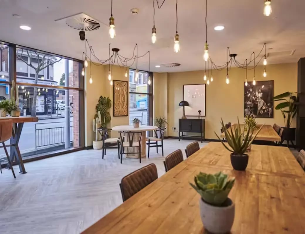 Wooden tables with plants and chairs communal area at York House in Nottingham Student Accommodation