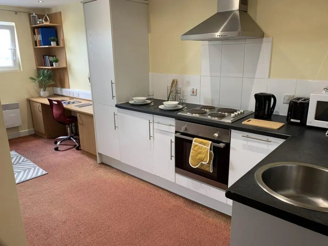 Desk chair shelves sink stove kettle toaster kitchen at Longside House Bradford in Bradford Student Accommodation