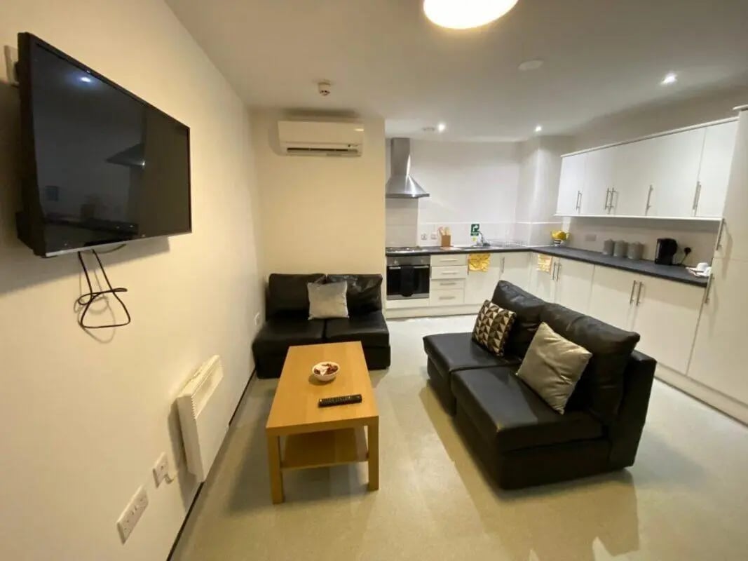 Living room with sofas kitchen area and TV living room at Longside House Bradford in Bradford Student Accommodation