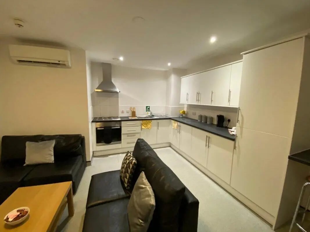 Black sofas kitchen appliances and cabinets living room kitchen at Longside House Bradford in Bradford Student Accommodation