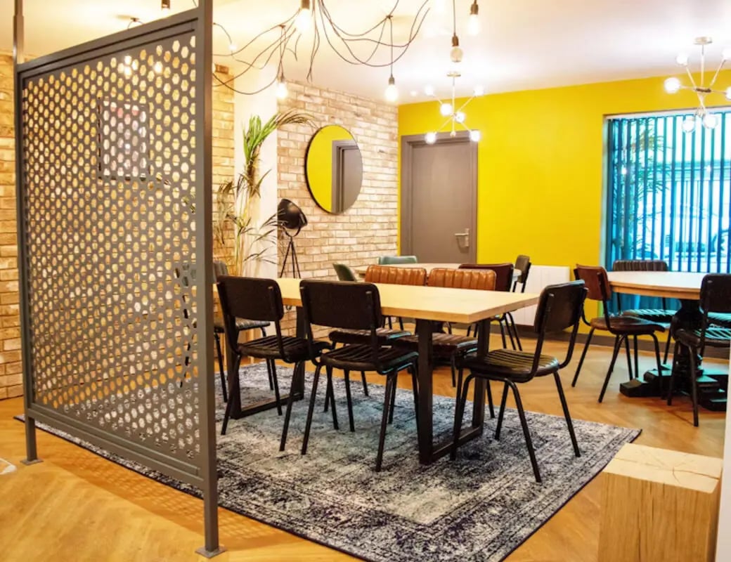 Modern dining tables chairs metal screen yellow wall communal area at St James Point in Newcastle Upon Tyne Student Accommodation