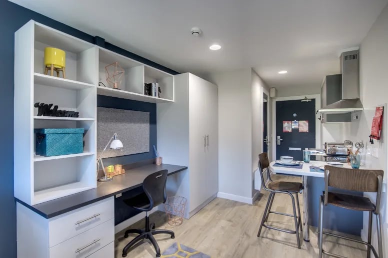 Desk shelves chair and kitchen area studio apartment at Riverside Quay in Stirling Student Accommodation