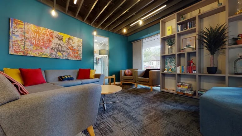 Gray sofas colorful pillows artwork bookshelves living room at Centro House in Stirling Student Accommodation