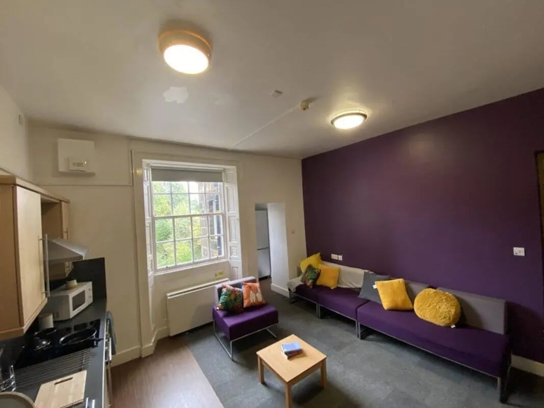 Kitchen counter purple couches coffee table living room at St Mary's Newcastle in Newcastle Upon Tyne Student Accommodation
