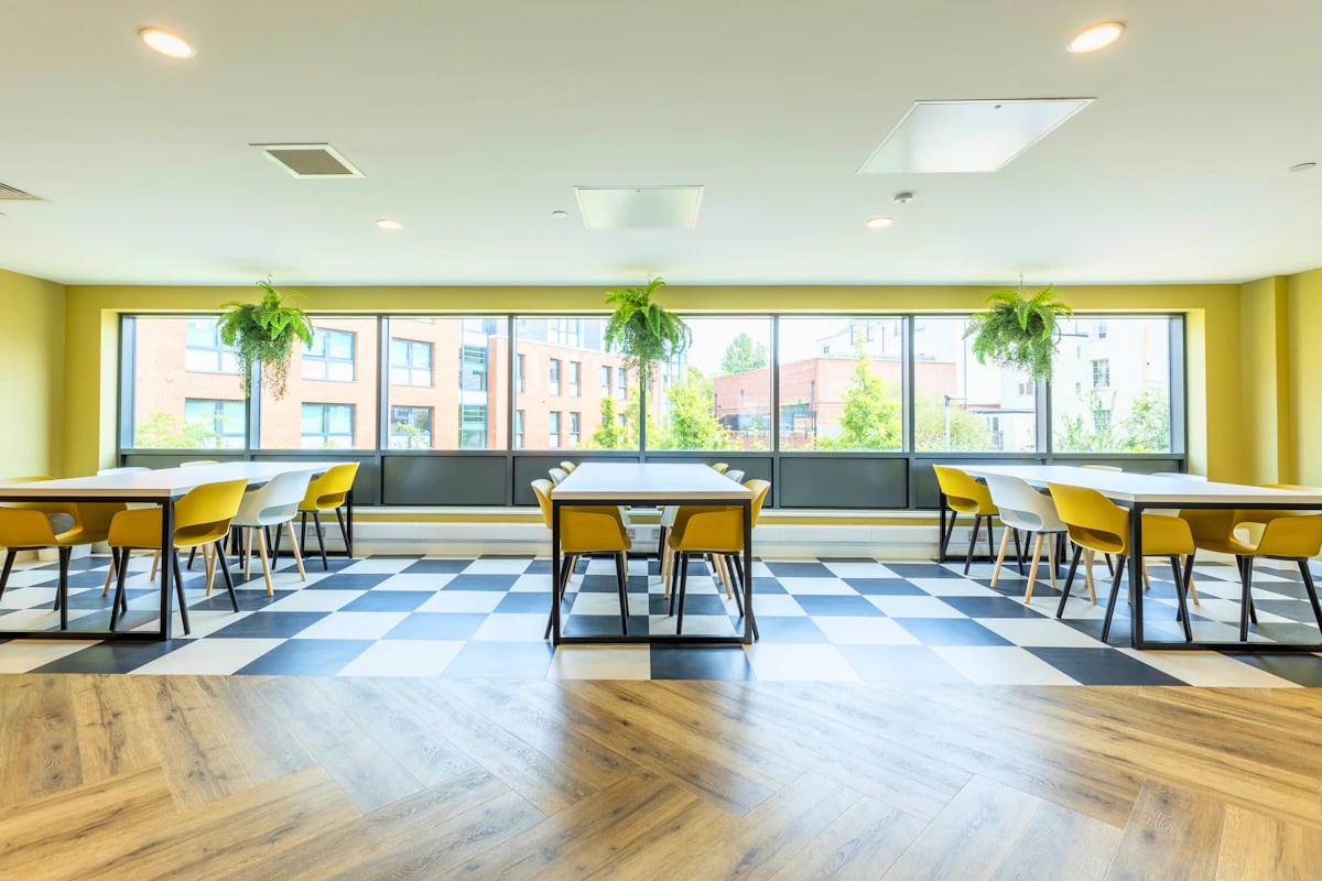 Tables and yellow chairs with plants Communal area at Clifford House in Exeter Student Accommodation