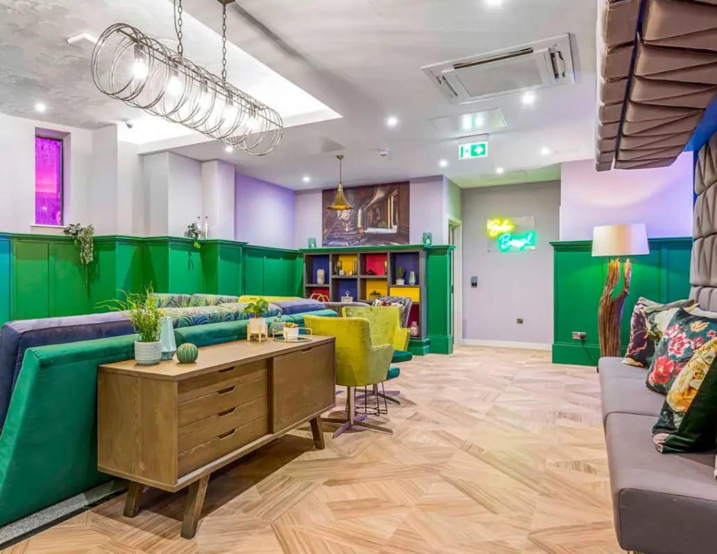 Modern lounge with green seating and wooden sideboard lounge area at Gravity in Lincoln Student Accommodation