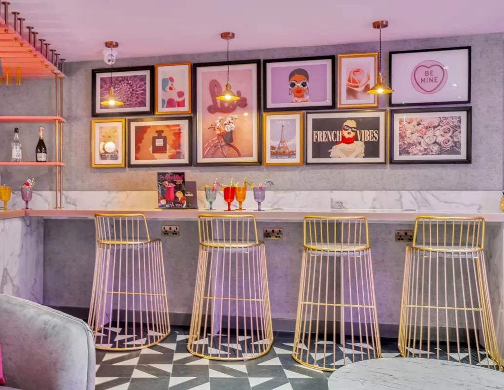 Four gold bar stools at counter with art and drinks bar area at Gravity in Lincoln Student Accommodation