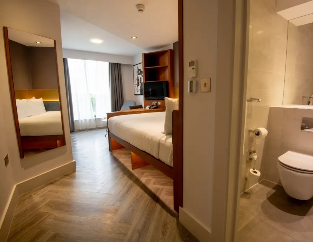 Bed mirror TV shelf and toilet bathroom at IconInc London Stratford in London Student Accommodation