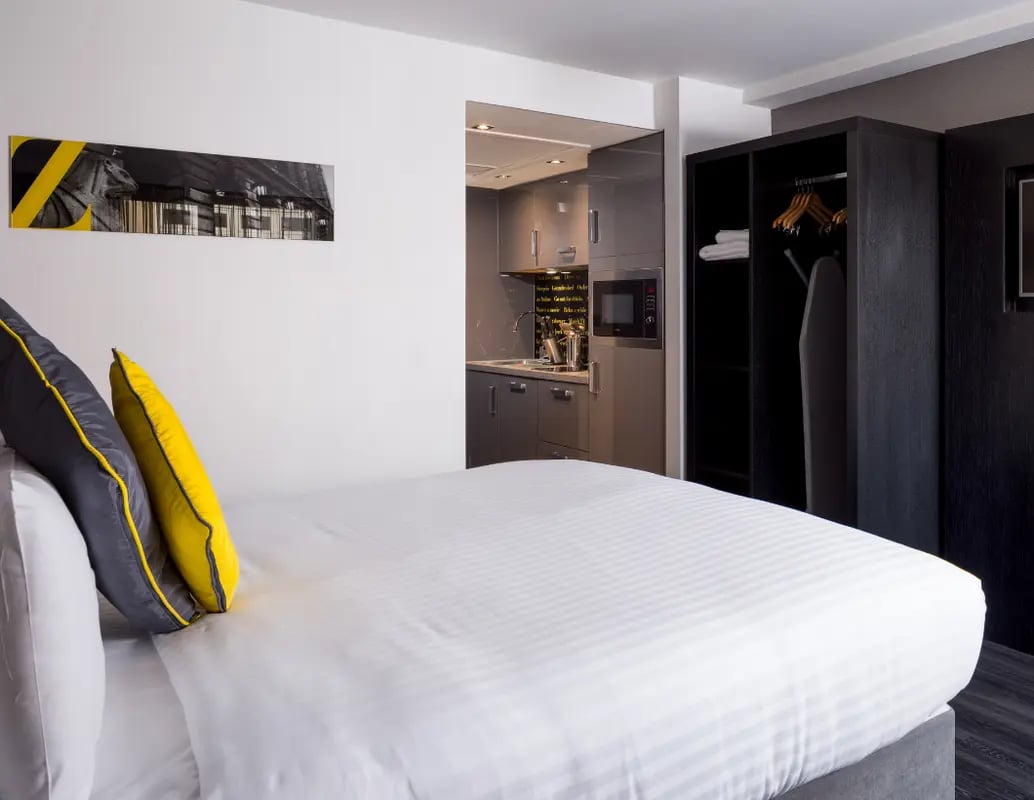 Bed with yellow pillows wardrobe kitchen area bedroom at IconInc Nottingham City in Nottingham Student Accommodation