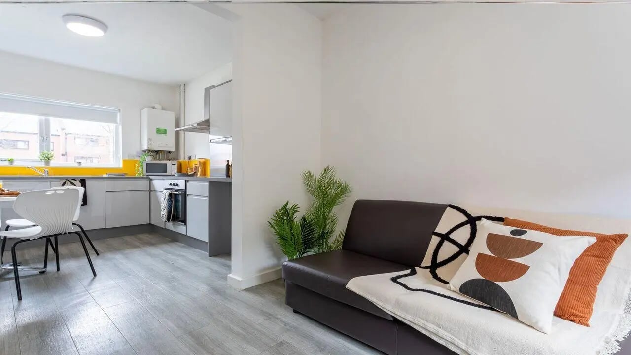 Kitchen and living area with sofa and pillows Living room at dwell Cathedral Campus in Liverpool Student Accommodation