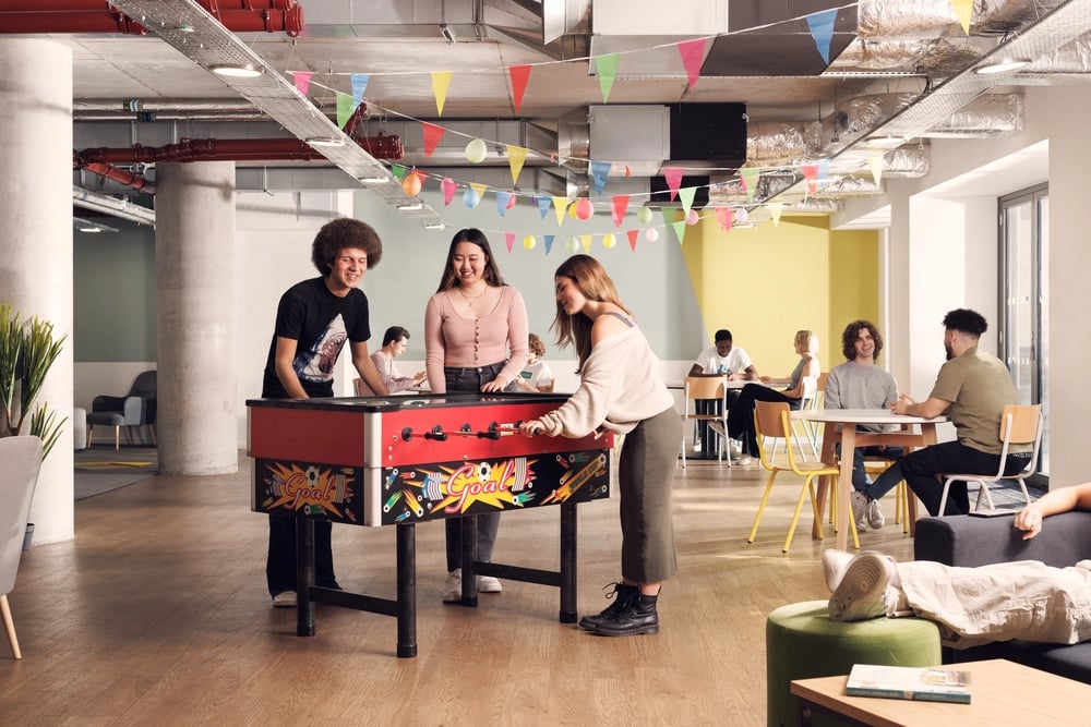 Students play foosball in common area living room at St Lukes View in Liverpool Student Accommodation