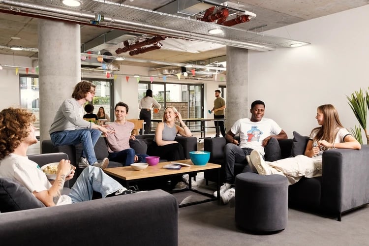 Students socialize on sofas near a coffee table living room at St Lukes View in Liverpool Student Accommodation