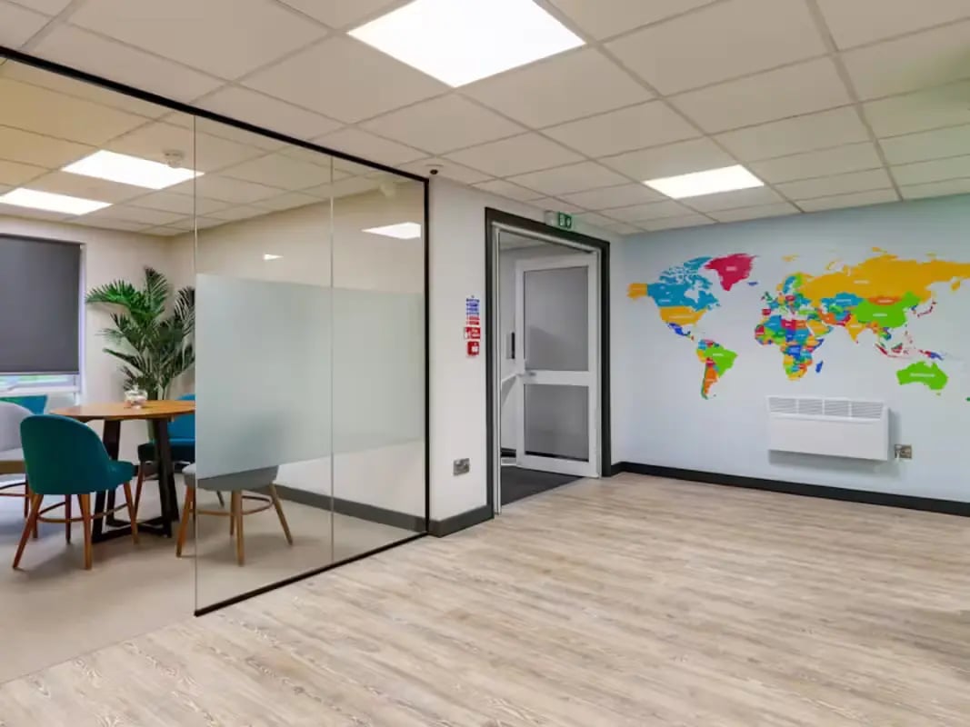 Glass room with table chairs and world map common area at Foundry Court in Preston Student Accommodation