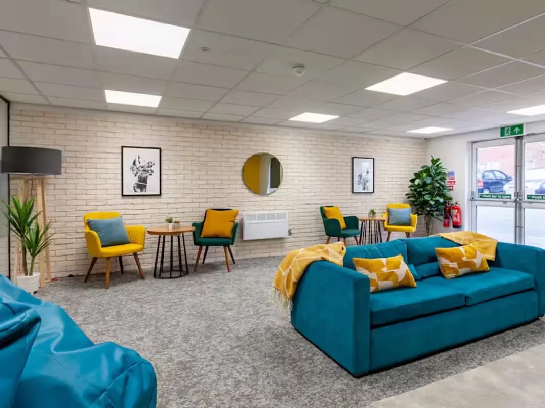 Teal couch with yellow blankets chairs tables living room at Foundry Court in Preston Student Accommodation