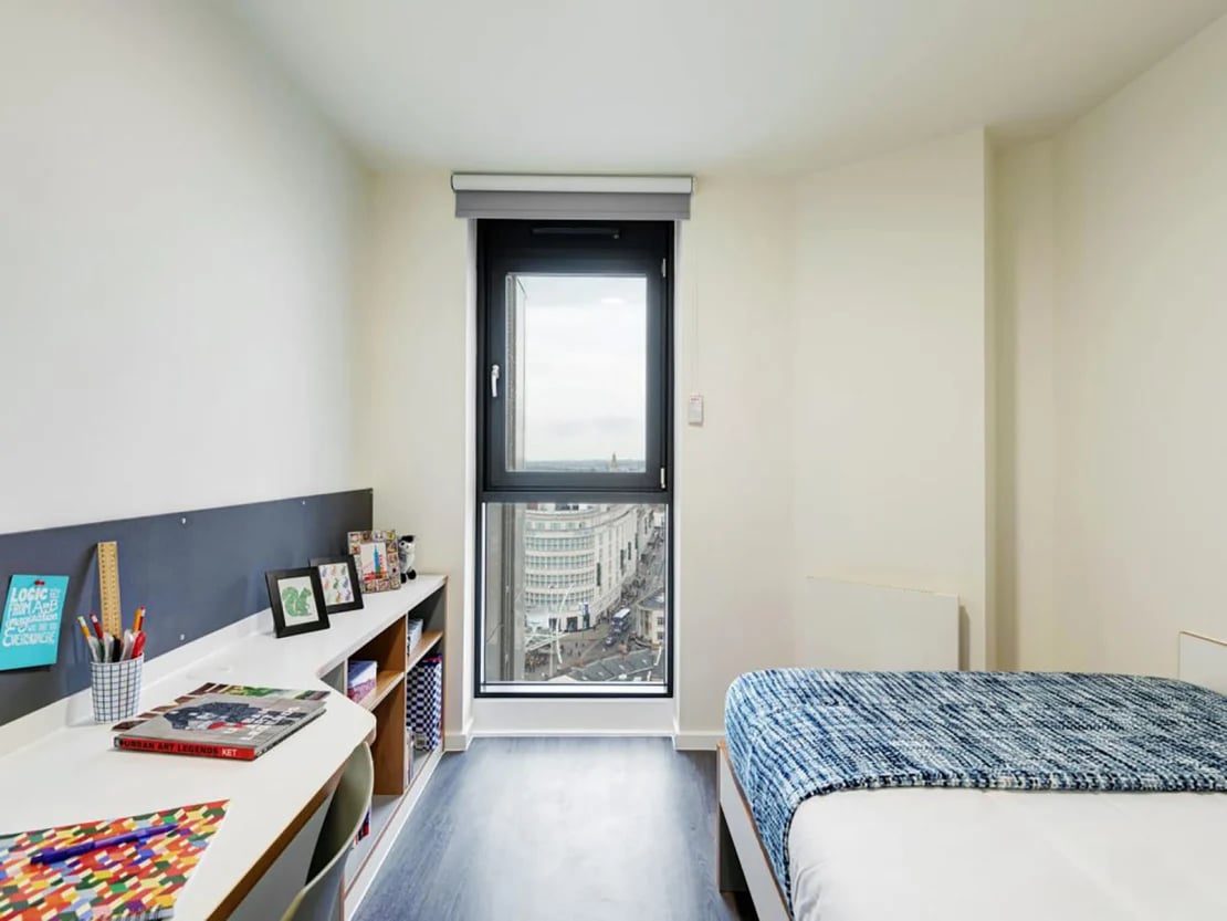 Desk with books and bed with blue blanket bedroom at New Bridewell in Bristol Student Accommodation