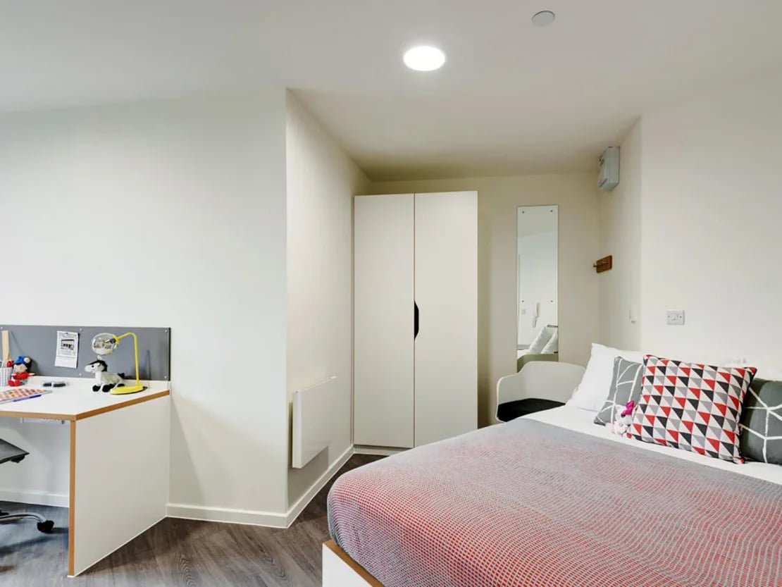 Desk wardrobe bed with patterned pillows bedroom at New Bridewell in Bristol Student Accommodation