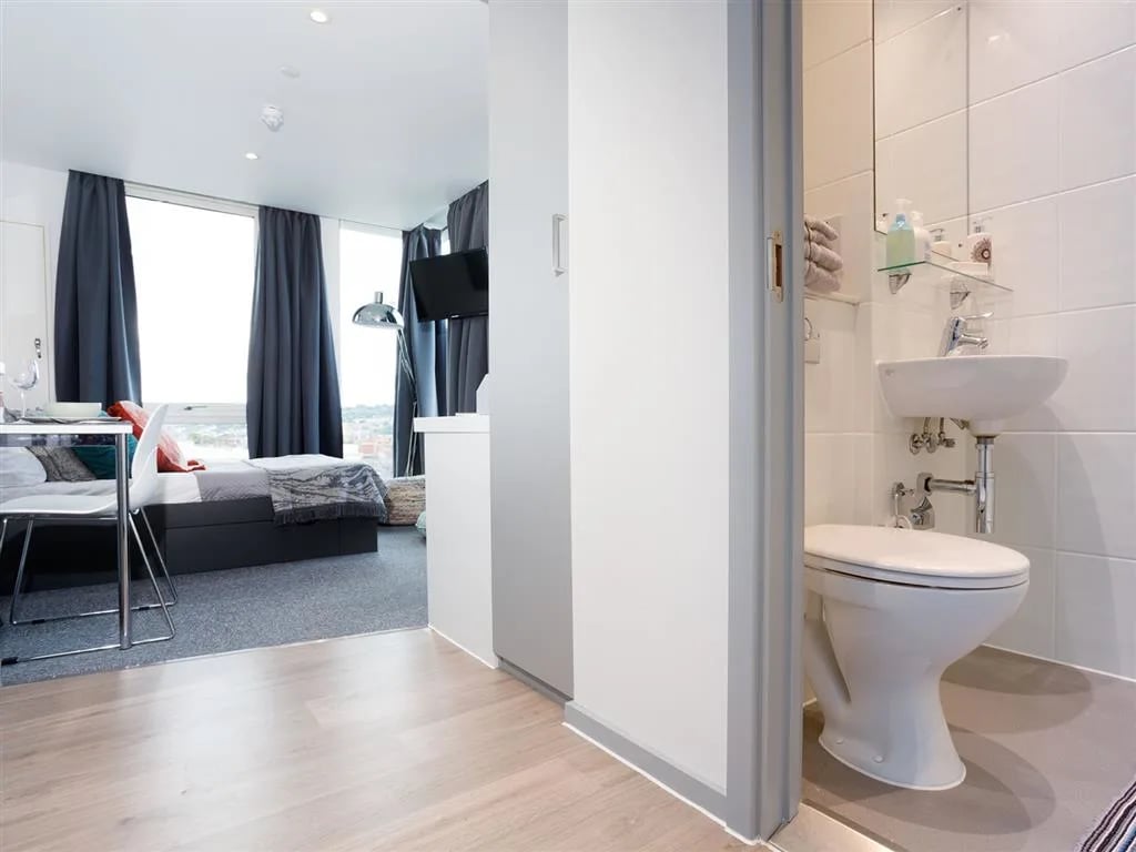 Bed TV desk chair and bathroom Bathroom at Queen Street Studios in Exeter Student Accommodation