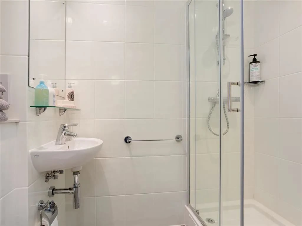 Sink shower bottles mirror and towels bathroom at Queen Street Studios in Exeter Student Accommodation