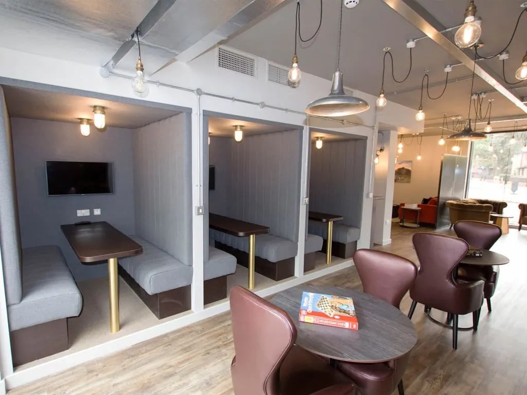 Pods with benches tables TVs and chairs communal area at The Shield in Newcastle Upon Tyne Student Accommodation