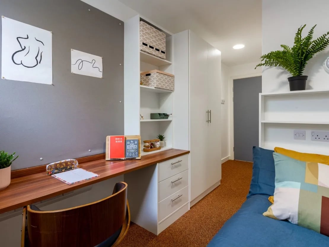 Desk with books plant closet bed and pillows bedroom at The Shield in Newcastle Upon Tyne Student Accommodation