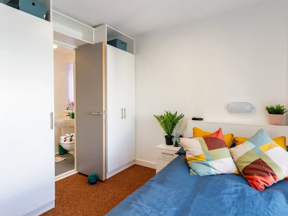 Bed with colorful pillows and open bathroom bedroom at The Shield in Newcastle Upon Tyne Student Accommodation