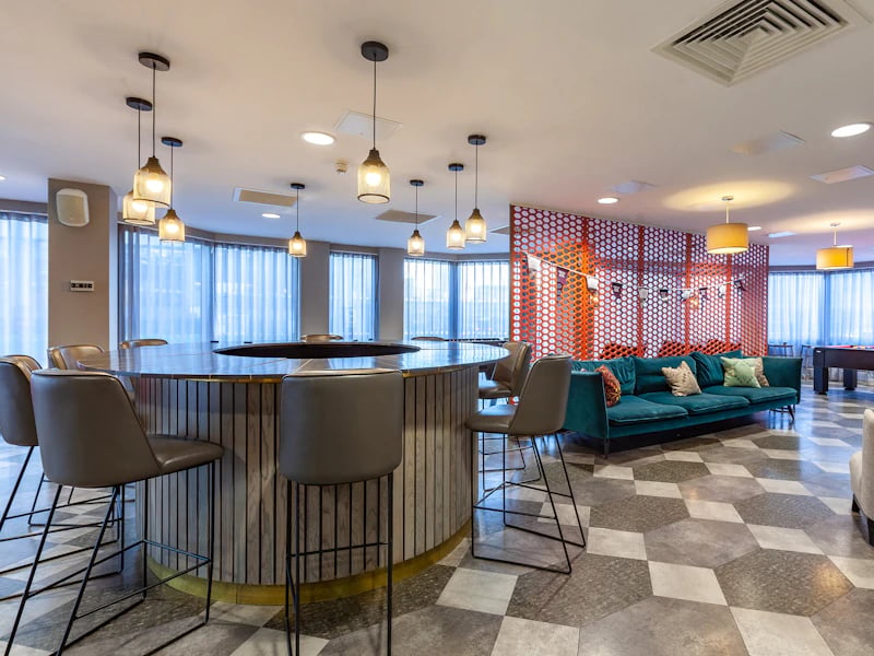 Round table with chairs teal sofa living room at The Fitzalan in Cardiff Student Accommodation