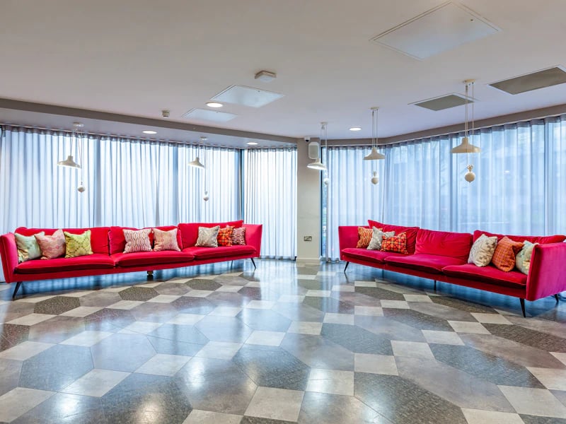 Two red sofas patterned cushions large window living room at The Fitzalan in Cardiff Student Accommodation