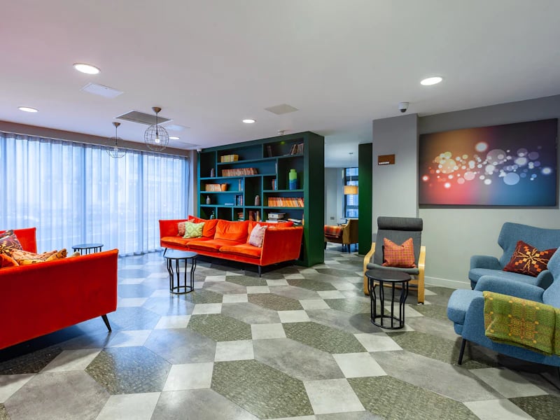 Orange sofas bookshelf and abstract art living room at The Fitzalan in Cardiff Student Accommodation