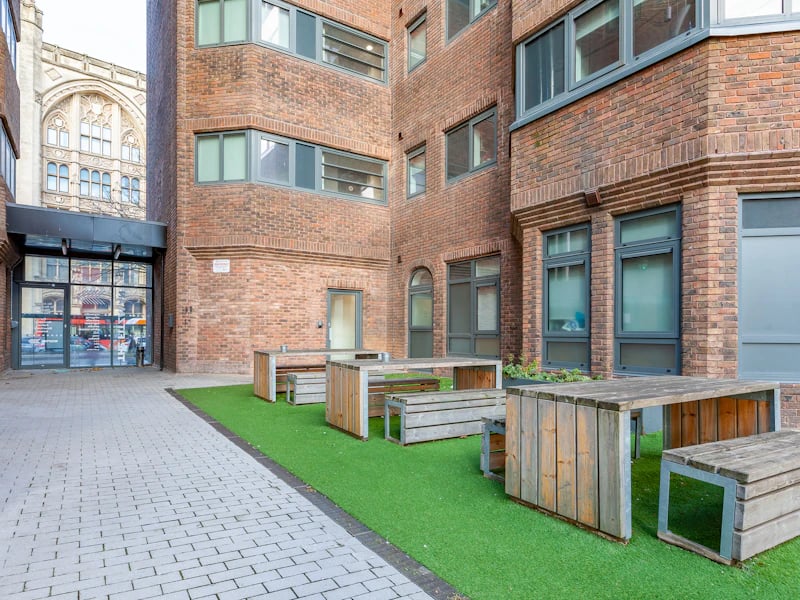 Wooden picnic tables on grass exterior at The Fitzalan in Cardiff Student Accommodation