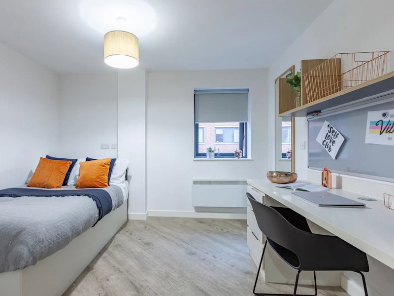 Bed desk lamp with orange pillows study bedroom at The Fitzalan in Cardiff Student Accommodation