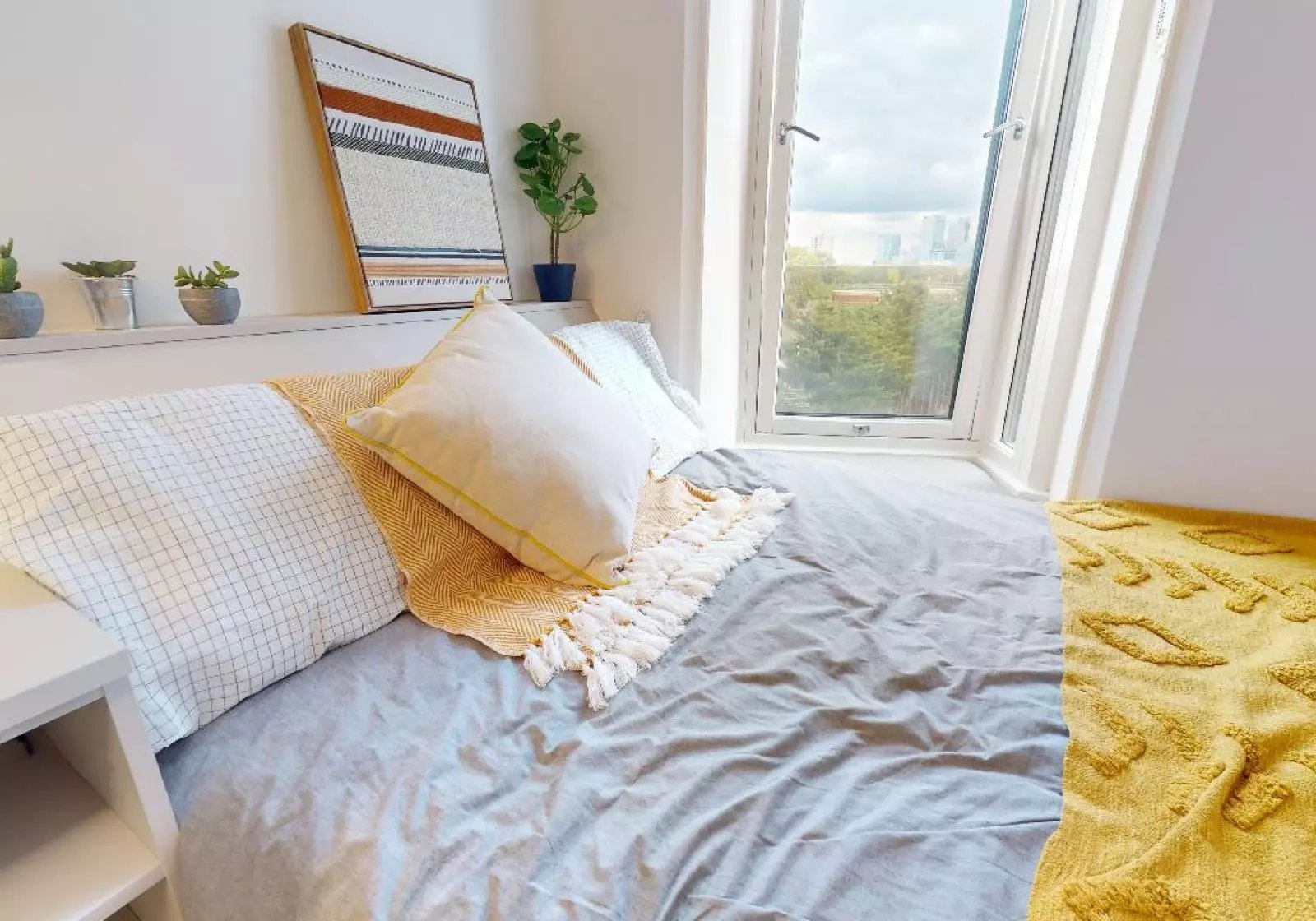 Bed with pillows and throws window view bedroom at iQ East Court in London Student Accommodation