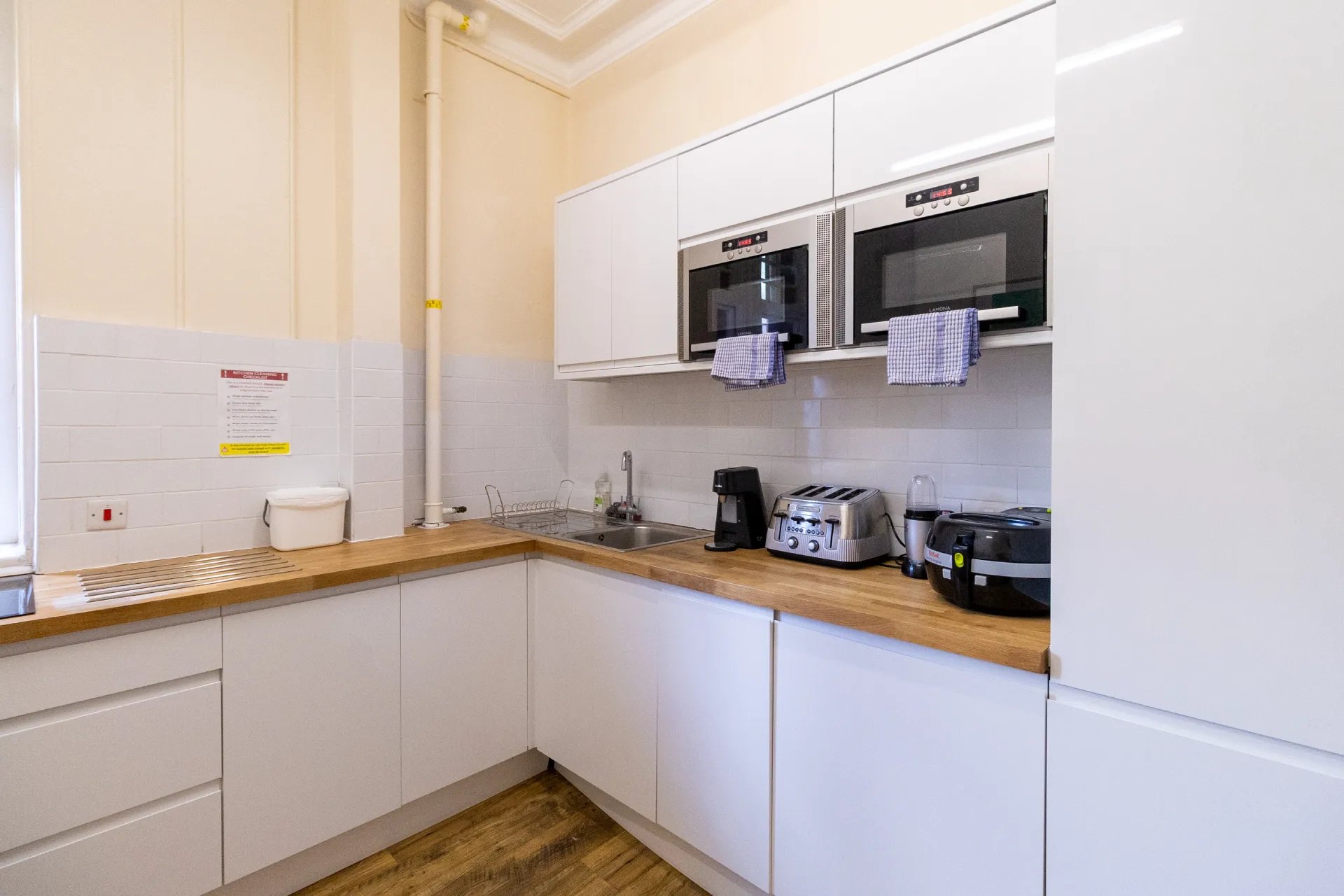 Two microwaves a sink and toaster kitchen at Queen Alexandra's House in London Student Accommodation