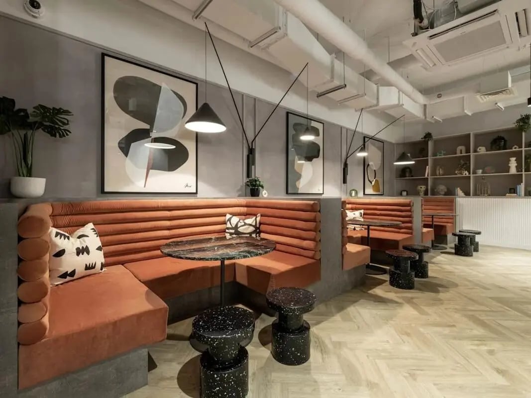 Orange banquette seating modern art and tables lounge area at Alma Place in Belfast Student Accommodation