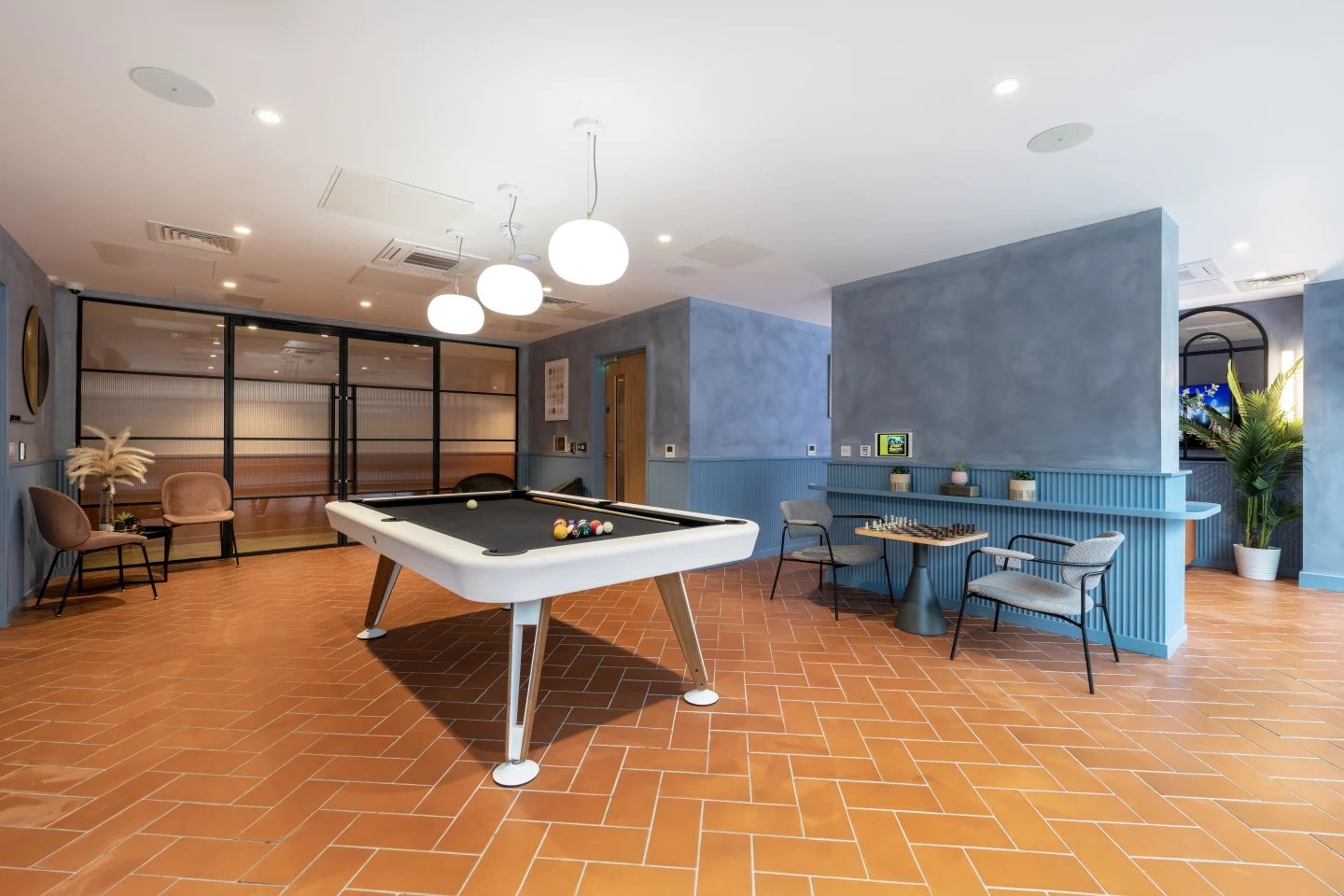 Pool table chairs chessboard and plant living room at Aster House in Belfast Student Accommodation