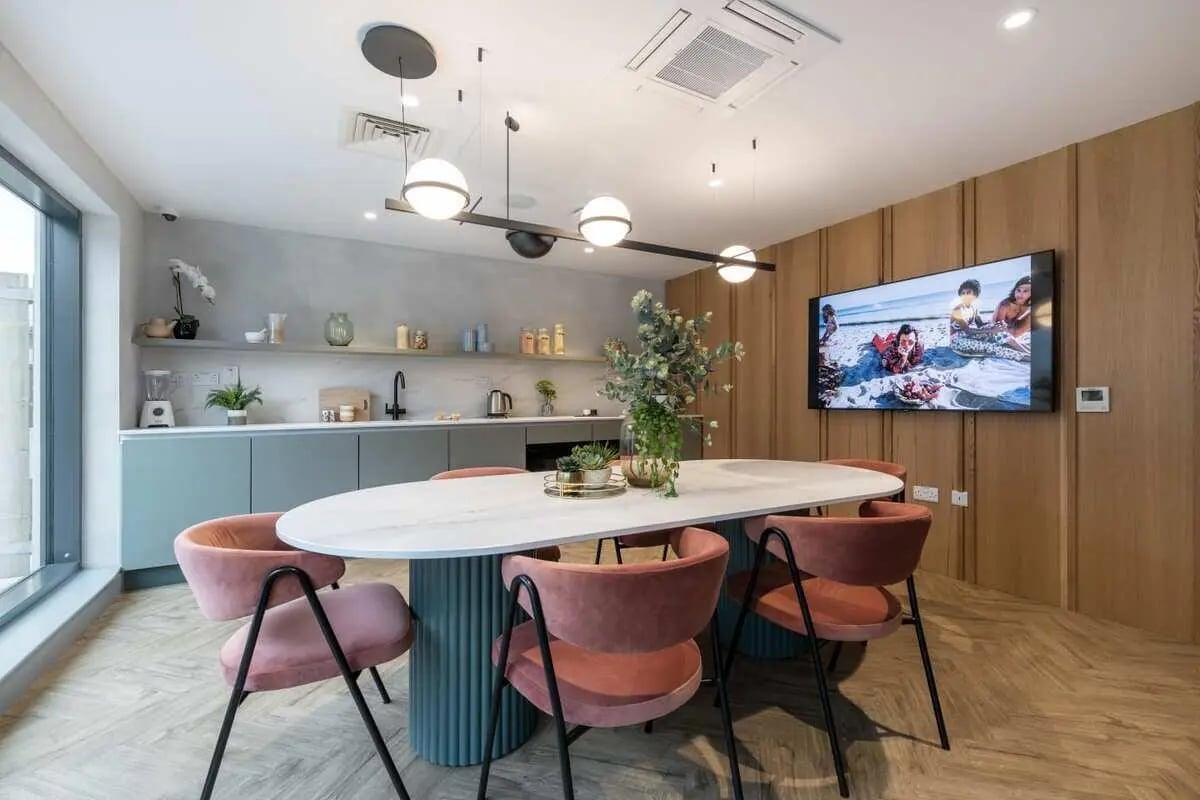 Oval dining table pink chairs television kitchen area at Aster House in Belfast Student Accommodation