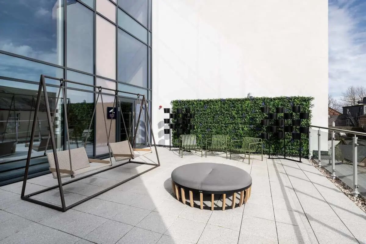 Swing chairs round ottoman chairs green wall exterior at Aster House in Belfast Student Accommodation