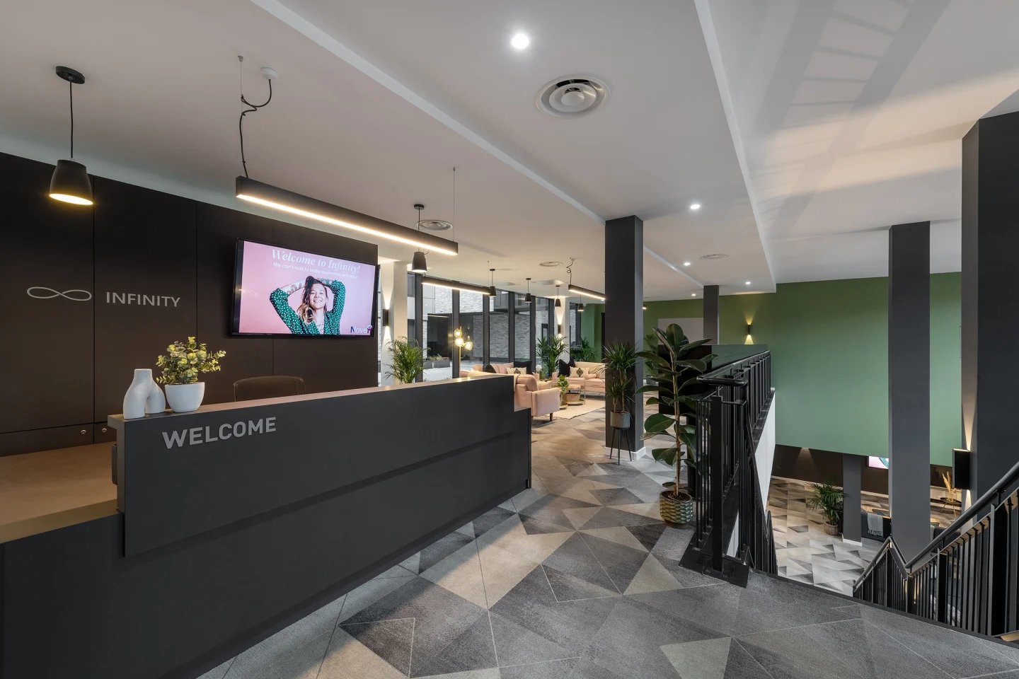 Reception desk with welcome screen and seating area. at Infinity Coventry in Coventry Student Accommodation