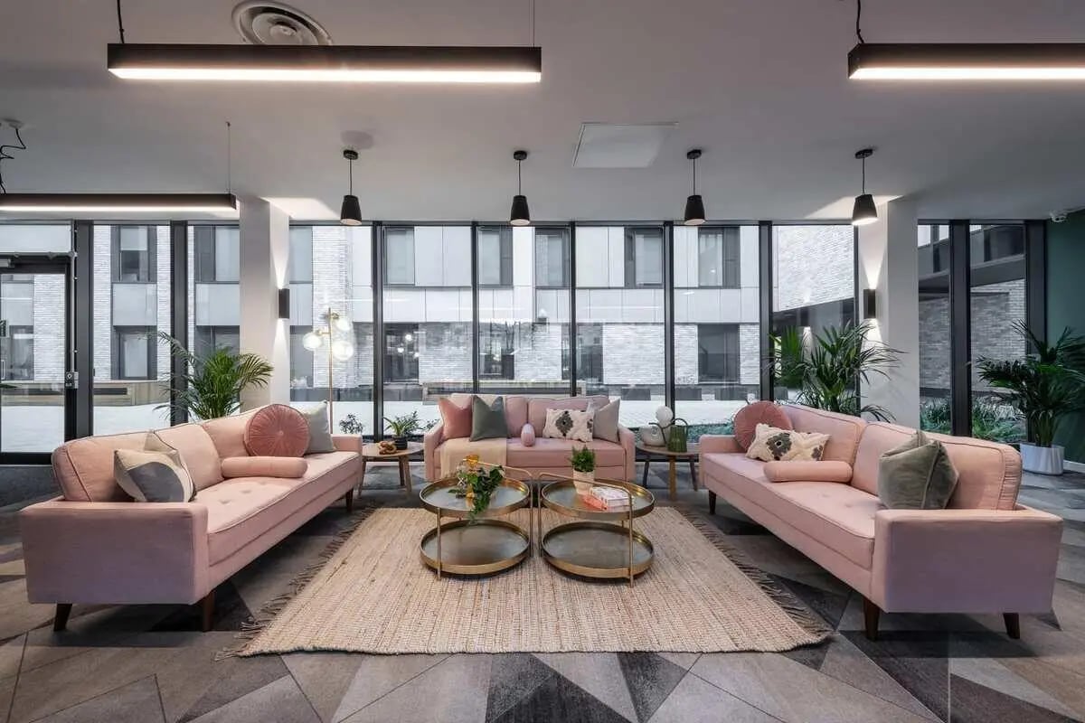 Three pink sofas with coffee tables and plants living room at Infinity Coventry in Coventry Student Accommodation