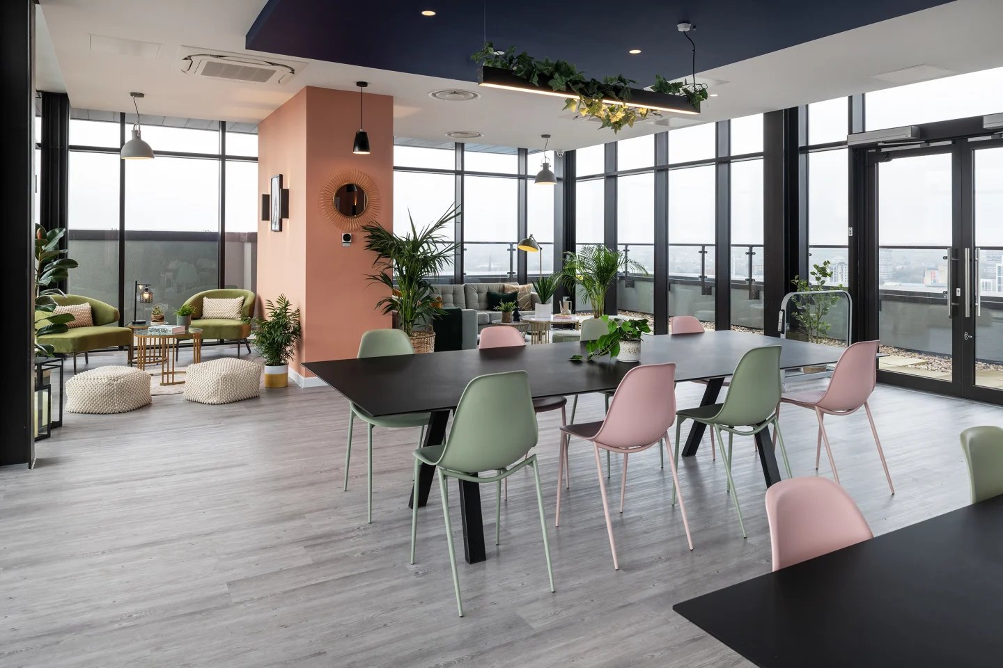 Dining area with pink and green chairs living room. at Infinity Coventry in Coventry Student Accommodation