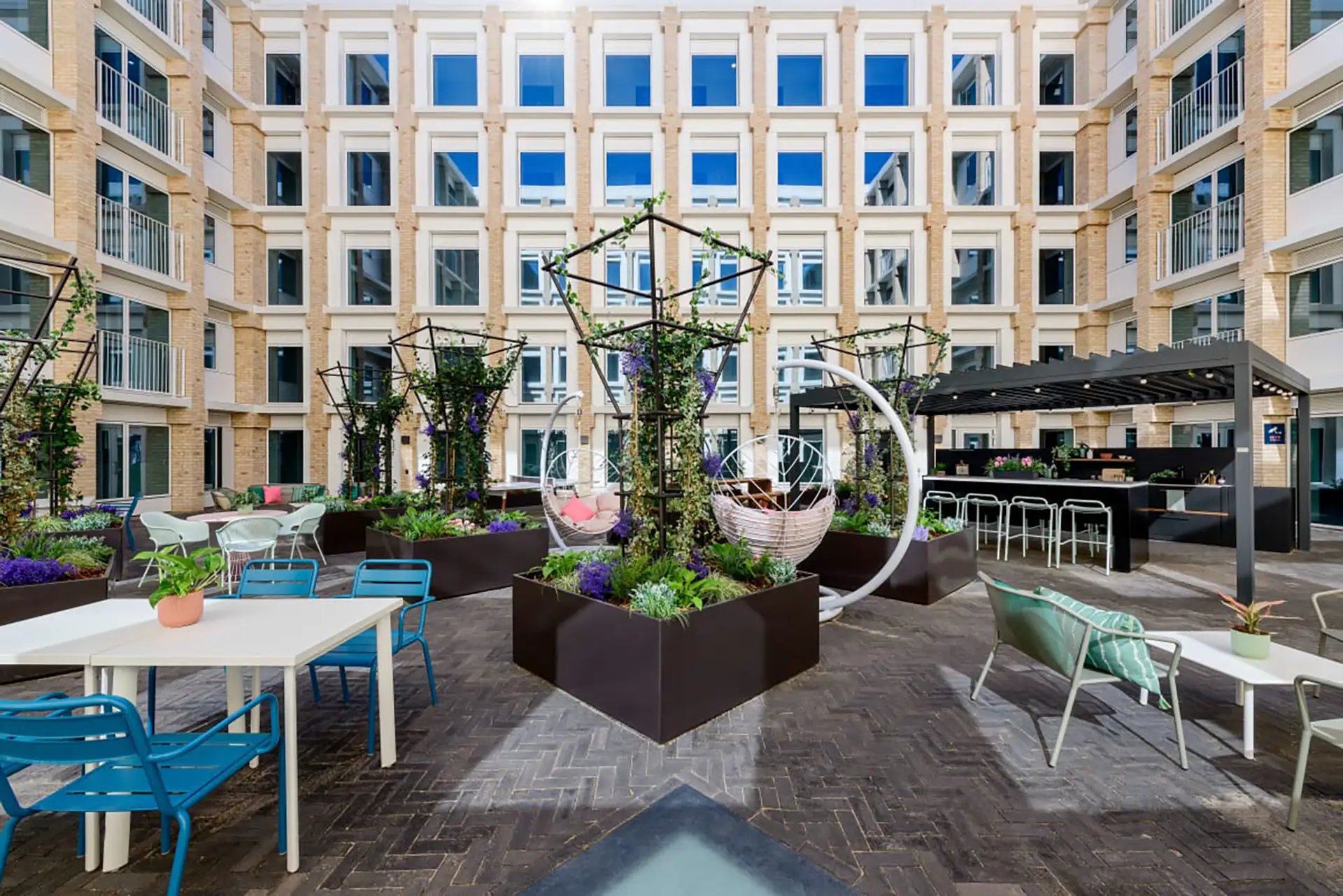 Courtyard with seating swing chairs and bar outdoor area at Wick Park in London Student Accommodation