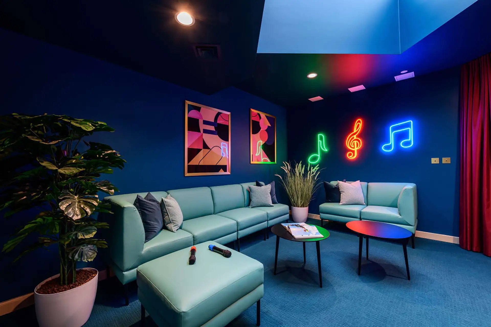 Blue sofas neon music notes artwork living room at Wick Park in London Student Accommodation