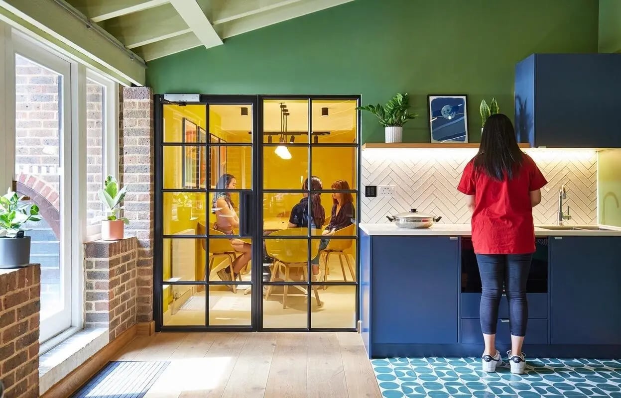 People in study room and woman cooking kitchen area at Scape Kings Cross in London Student Accommodation