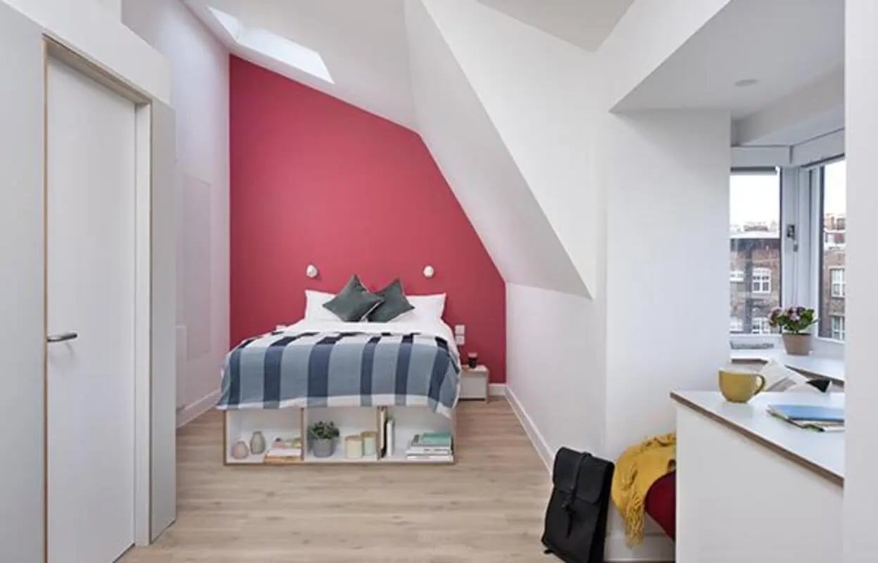 Bed with striped blanket and study area bedroom at Scape Kings Cross in London Student Accommodation
