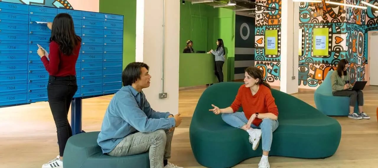 Students near mailboxes and colourful murals communal area at Scape Mile End Canalside in London Student Accommodation