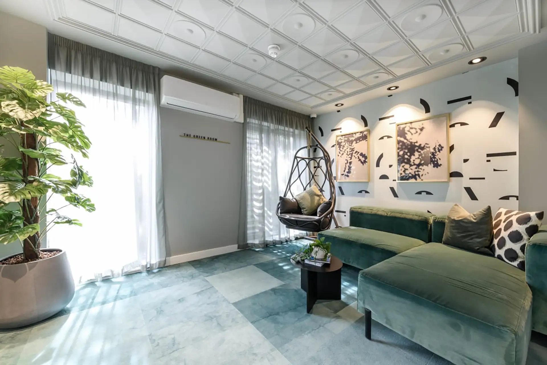 Green sectional sofa hanging chair patterned wallpaper living room at Huxley Studios in Edinburgh Student Accommodation