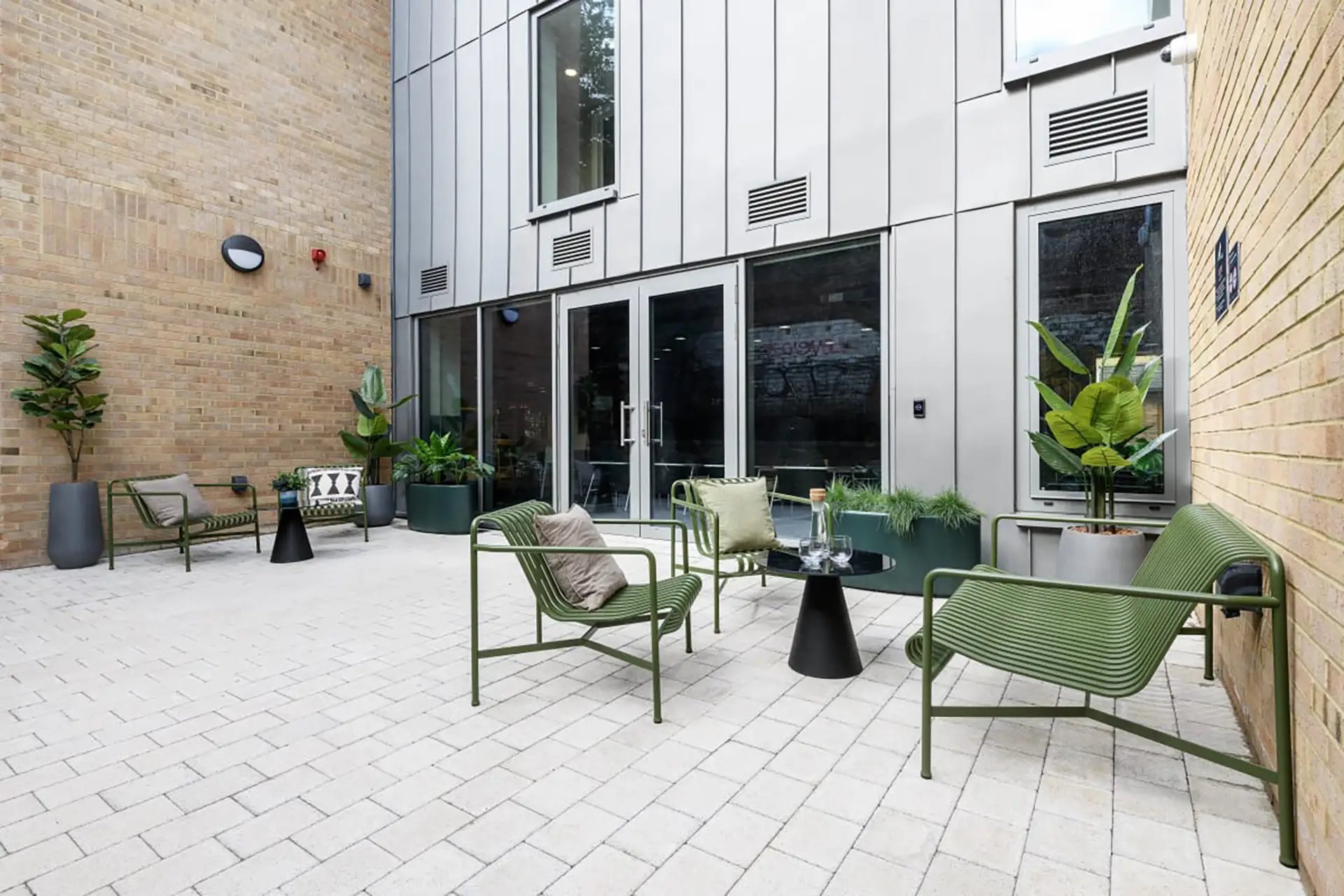 Green chairs table plants courtyard patio at Huxley Studios in Edinburgh Student Accommodation